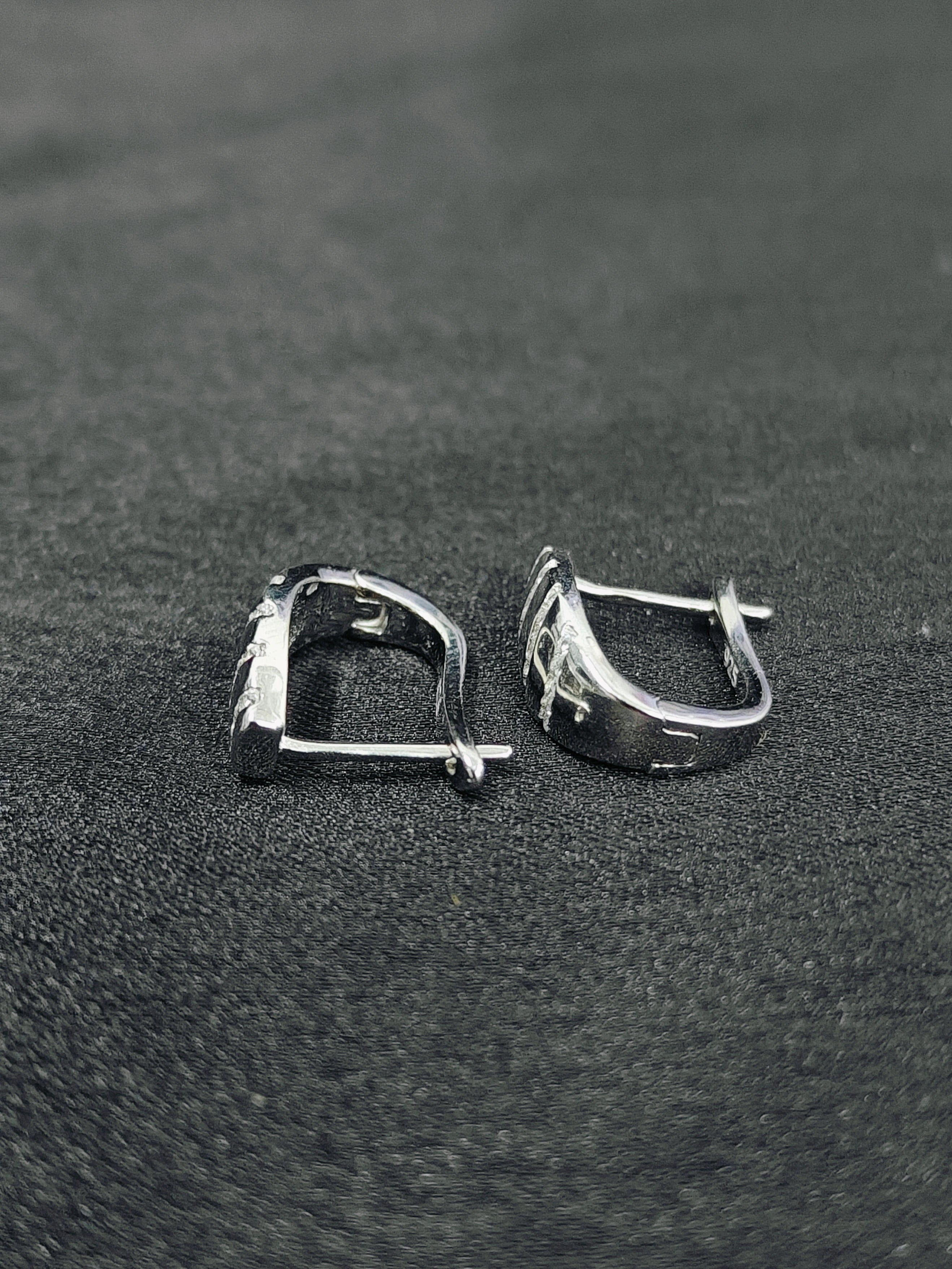 Pair of silver hoop earrings on a black textured surface